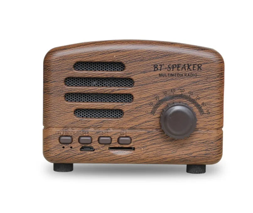 Vintage-style wooden finish Bluetooth speaker on a wooden table next to a plant.