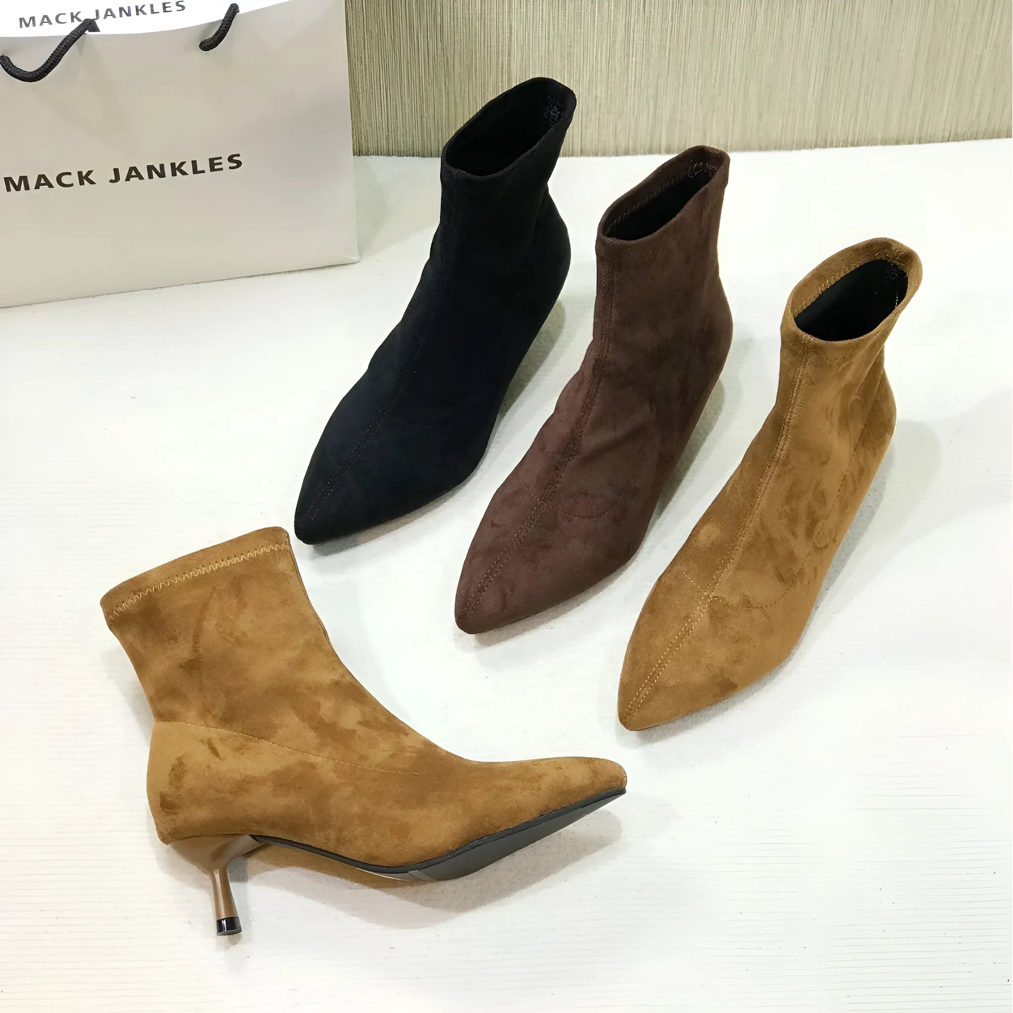 Black pointed toe women's ankle boot with a stiletto heel on a plain background.
