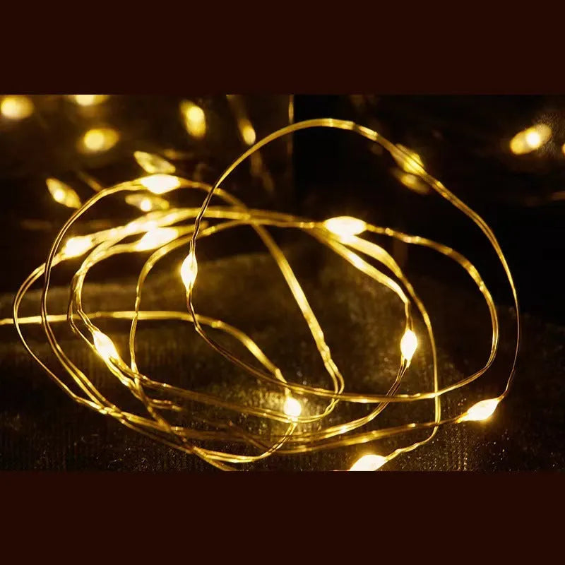 LED copper wire light string with warm white floral-shaped lamps on a dark background