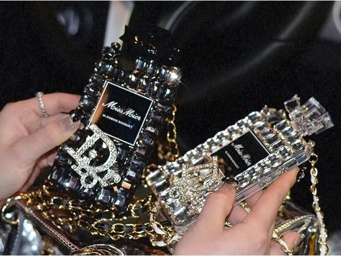 iPhone case with a perfume bottle and bow charm on a metal chain, in black colour with textured TPU shell.