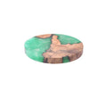 Set of solid wood coasters for tea, showing round green and black versions on a wooden table.