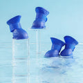 Set of four waterproof silicone dog rain boots in dark blue, gray, light blue, and pink on a white background