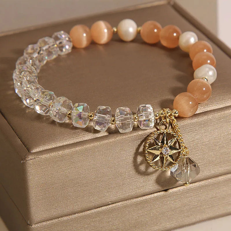 Gold-plated women's bracelet with an eight Awn star charm holding an inlaid orange opal crystal.