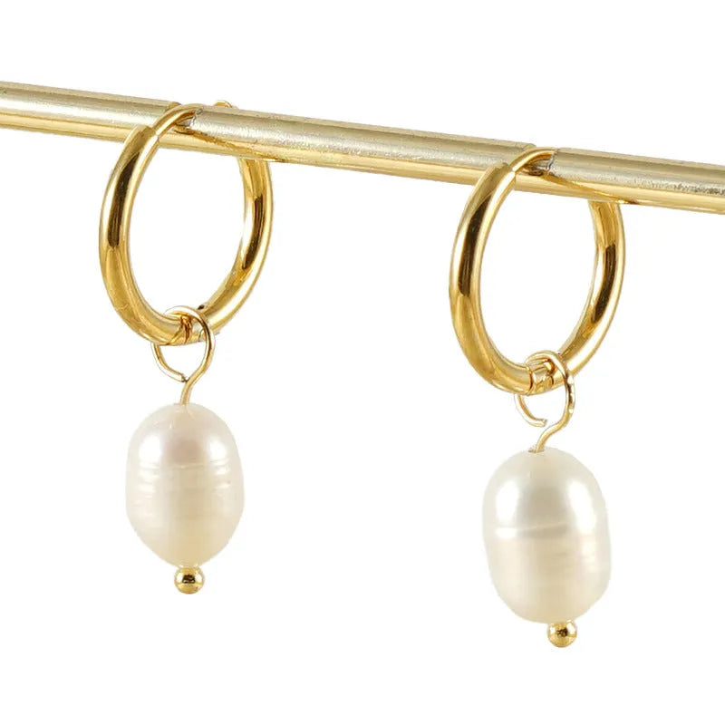A pair of gold-colour geometric drop earrings with white pearl accents on a stainless steel post.