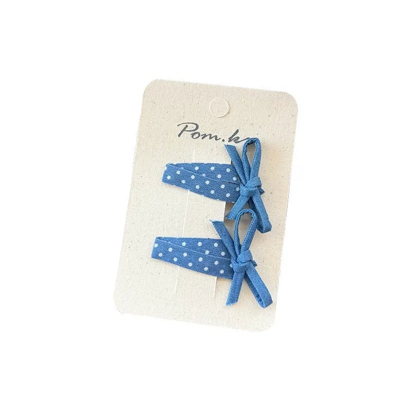 One pair of children's cloth hair clips with bow and flower detailing, shown in a choice of five styles and two clip sizes.