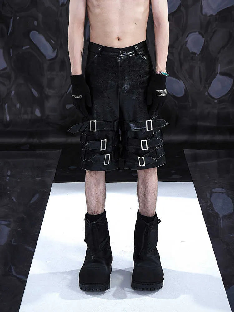Black men's cropped PU leather shorts with ring detail on a hanger