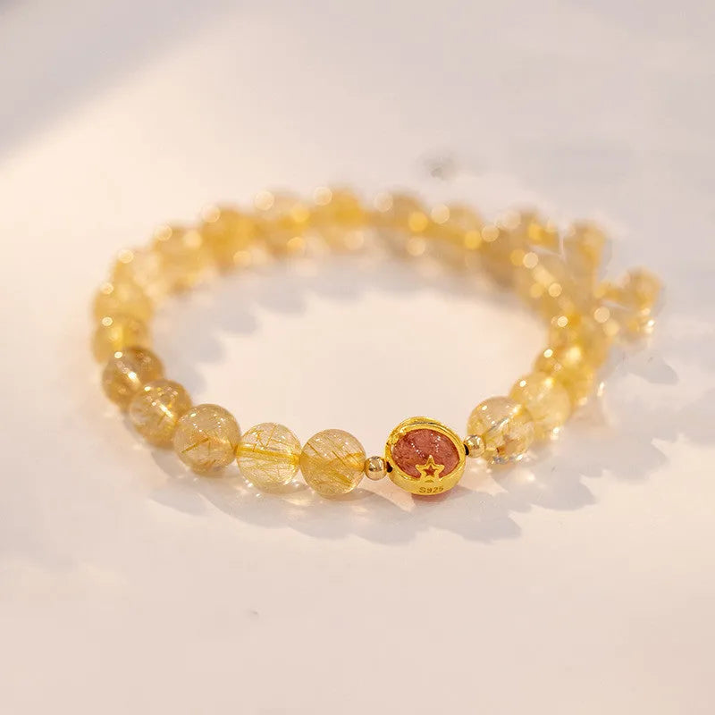 Citrine and gold rutilated quartz bracelet with diamond faceted beads on a wrist.