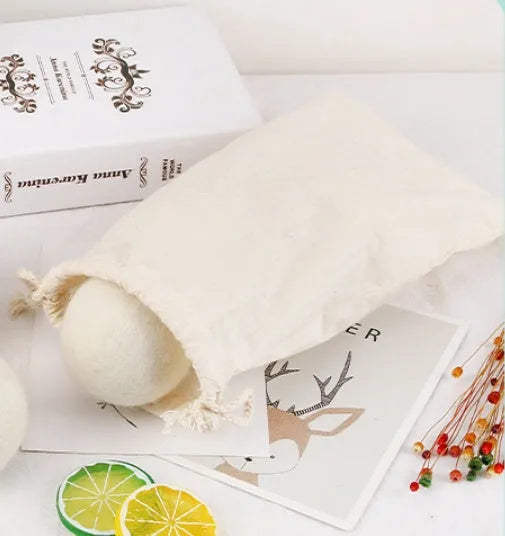 Set of wool laundry drying balls next to cotton storage bag for tumble dryers