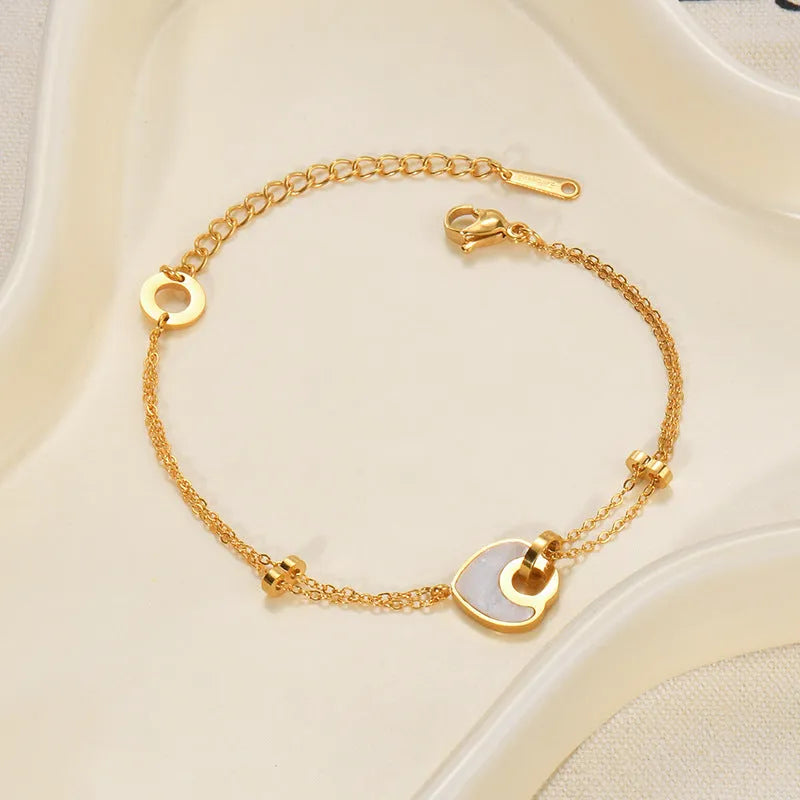 Close-up of a women's stainless steel bracelet with a double-layered heart pendant.