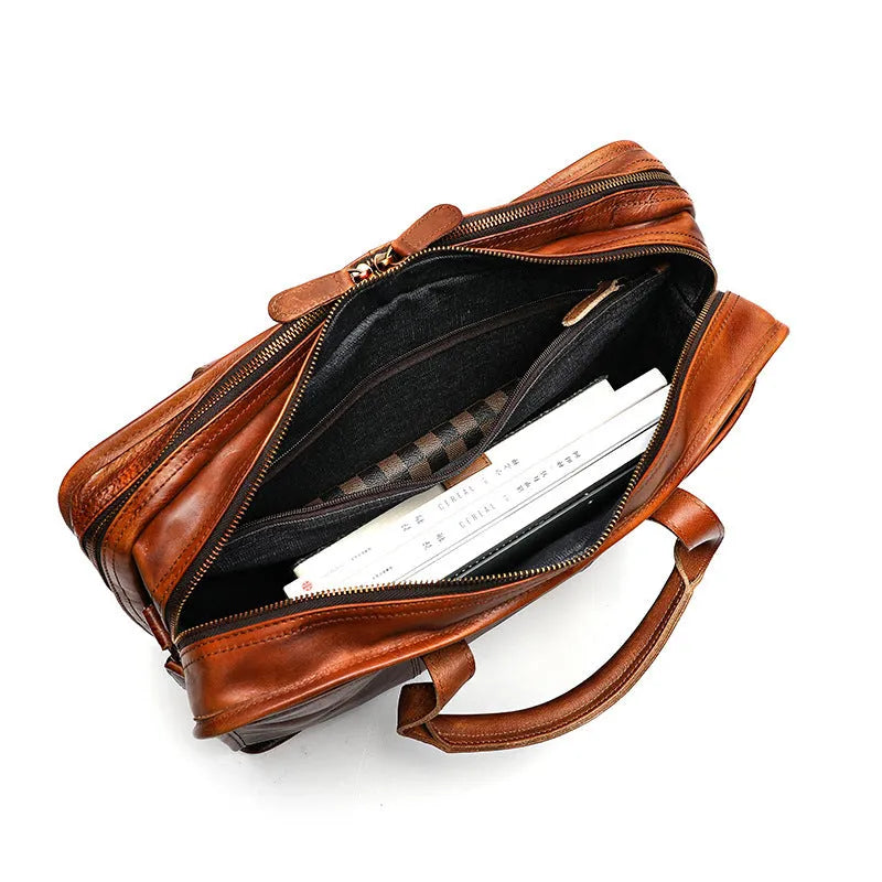 Brown vintage leather men's briefcase with soft handle, showing organised internal pockets for laptop and camera.
