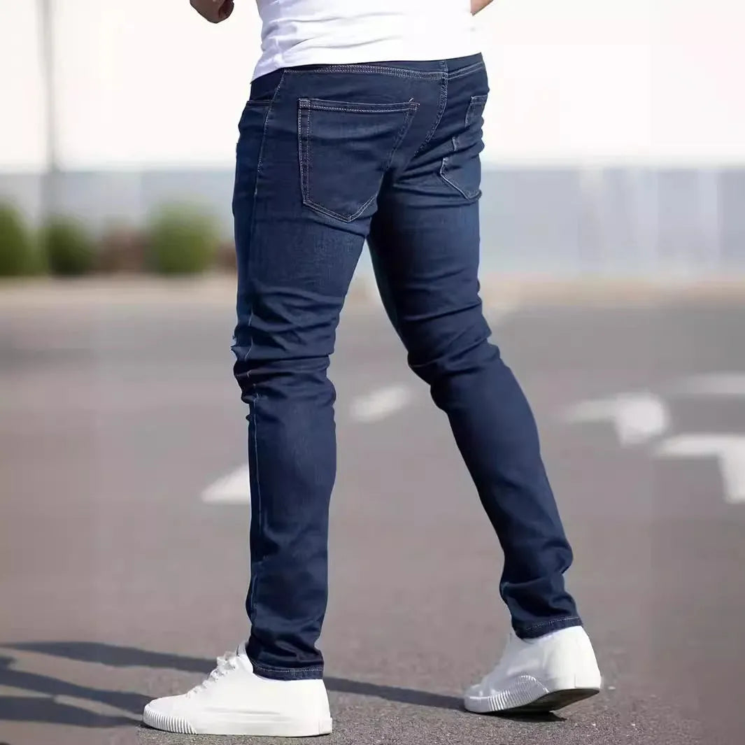 Men's dark blue skinny-fit cotton jeans with a mid-rise waist and zipper fly on a plain background.