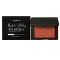Matte silky blush in dark red shade in a compact powder pan with a brush nearby.