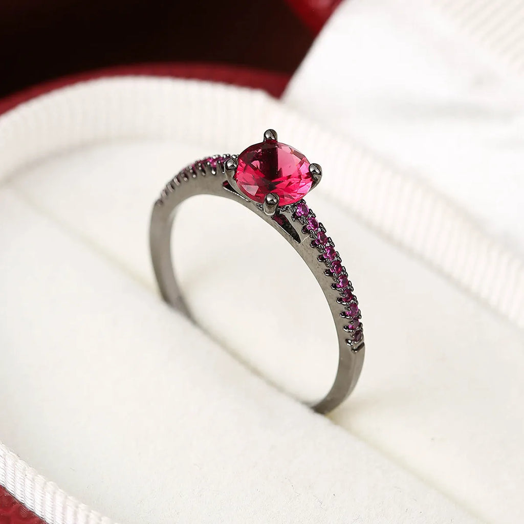 A geometric hexagonal copper ring with a central zircon stone, shown in a gun black and rose red electroplated finish.
