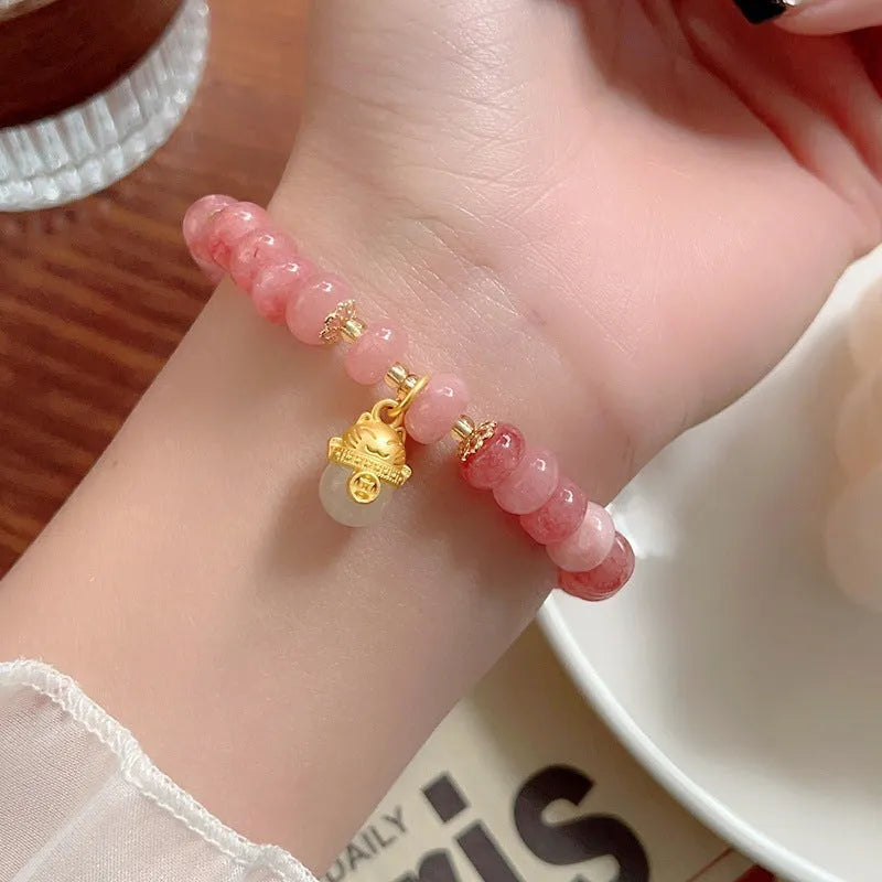 Women's retro strawberry quartz bracelet with lucky cat charm on wrist