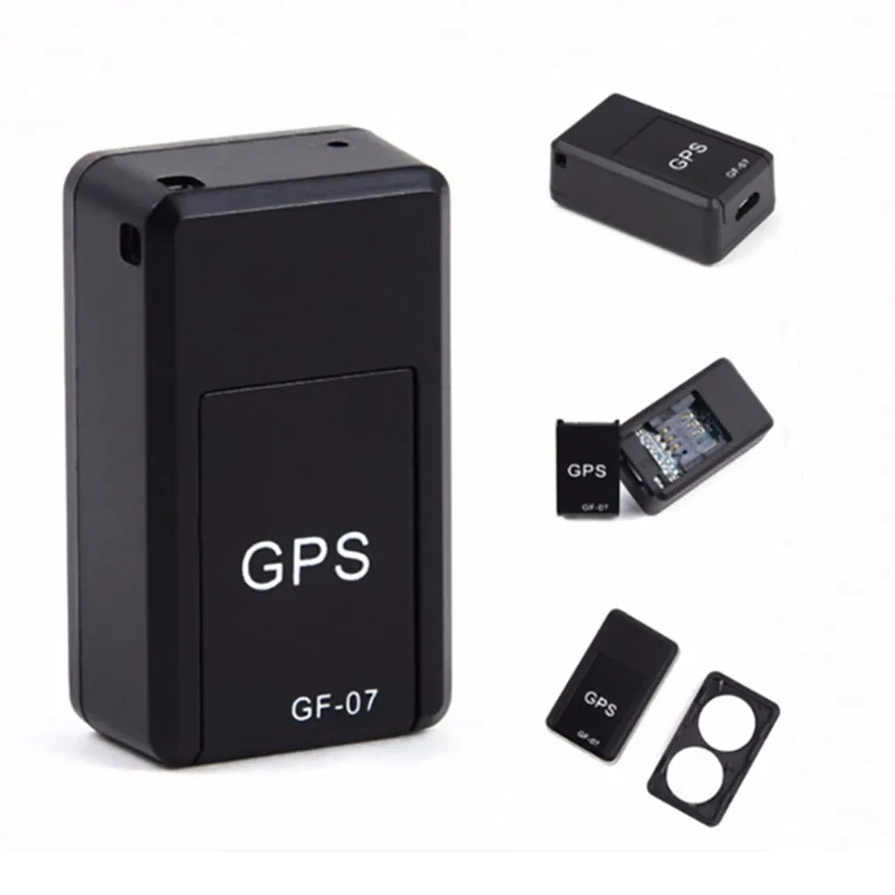 Small black magnetic GPS tracker device next to a USB charging cable on a table.