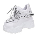 White women's low-top platform sports trainers with mesh panels and a black cross-strap on a rubber sole.