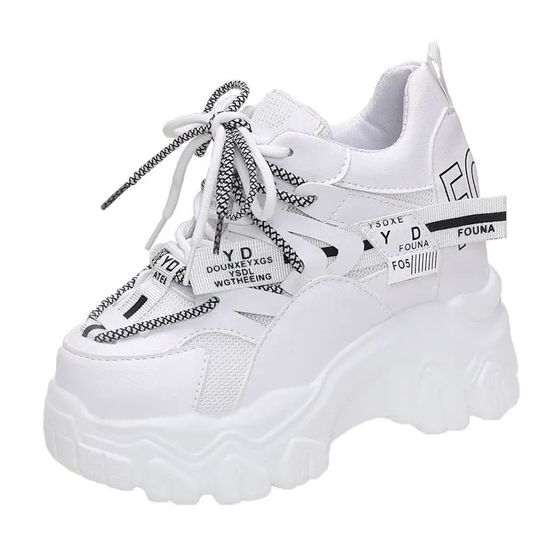 White women's low-top platform sports trainers with mesh panels and a black cross-strap on a rubber sole.