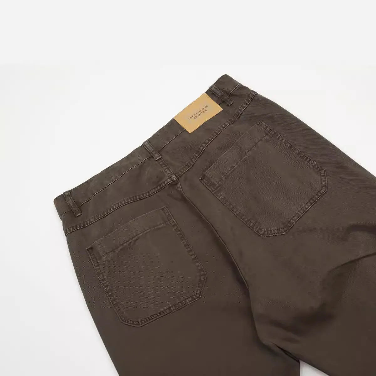 Men's brown loose-fit high-waisted straight-leg cotton trousers on a hanger.