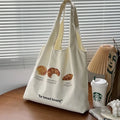 Beige canvas shoulder tote bag with a decorative bread and croissant print design.