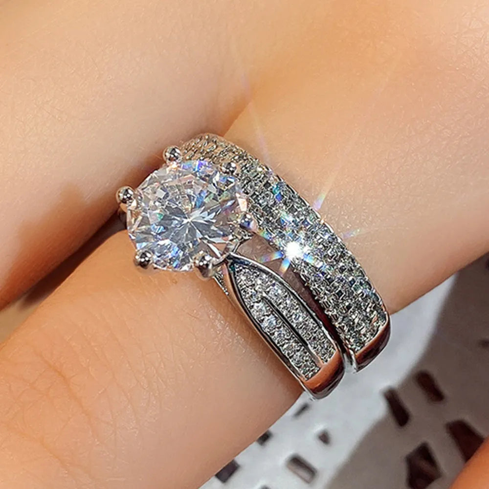 A geometric white gold-coloured alloy wedding ring bracelet on a finger, showing its continuous band design with a round detail.