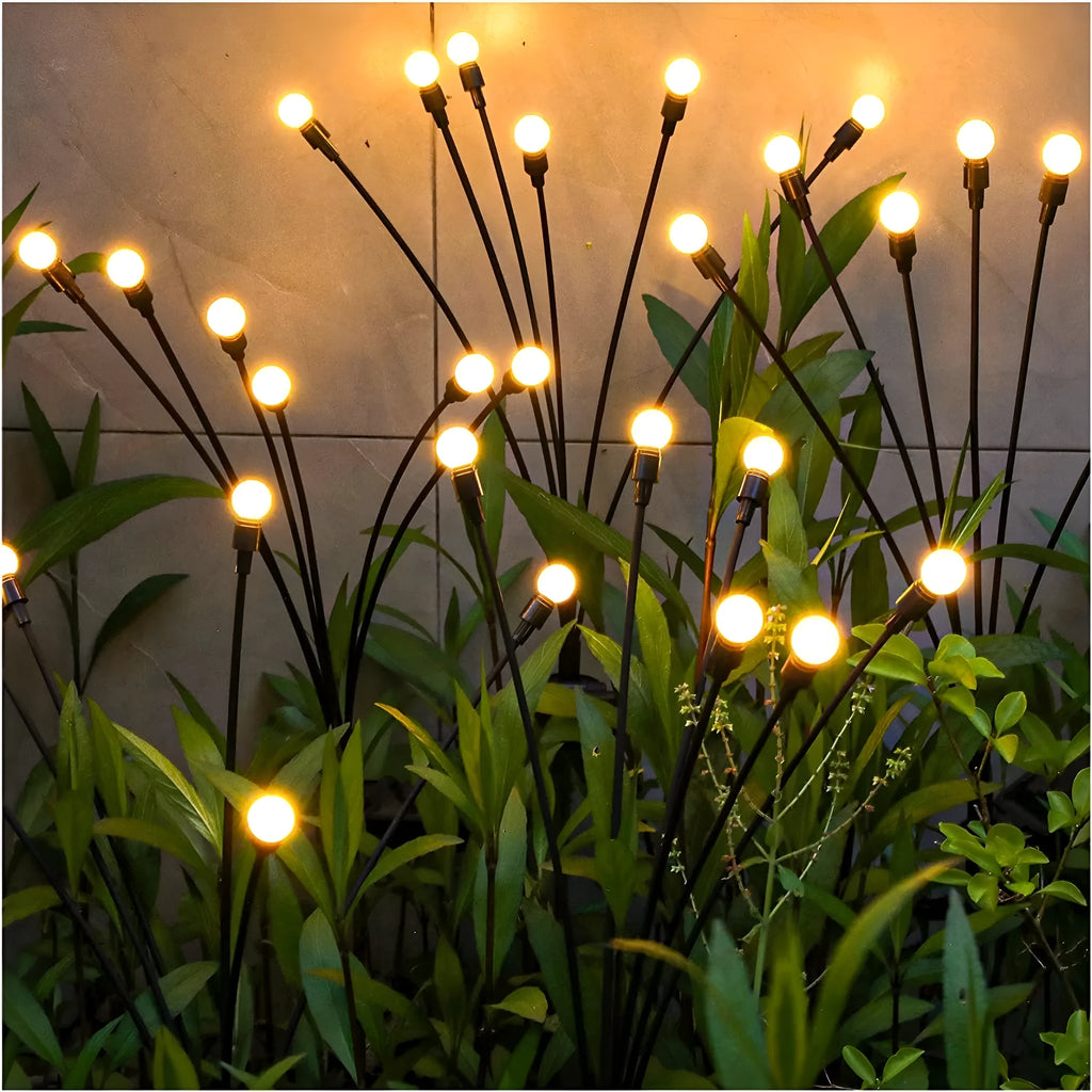 Solar-powered LED garden ground light with stainless steel spike, lit up in a lawn at dusk.
