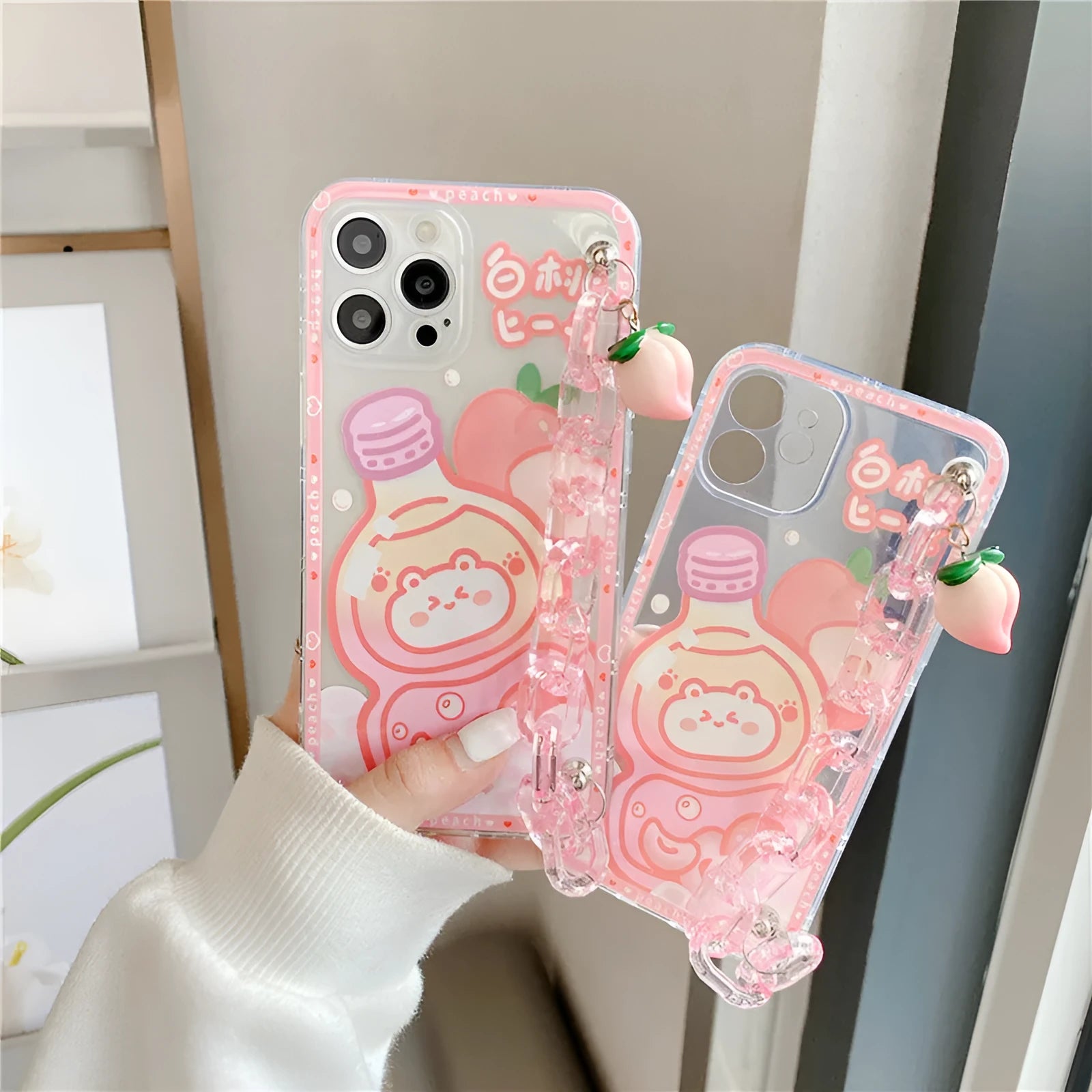 White silicone iPhone case with cartoon peach juice drink and bear design, shown with attached wrist strap.