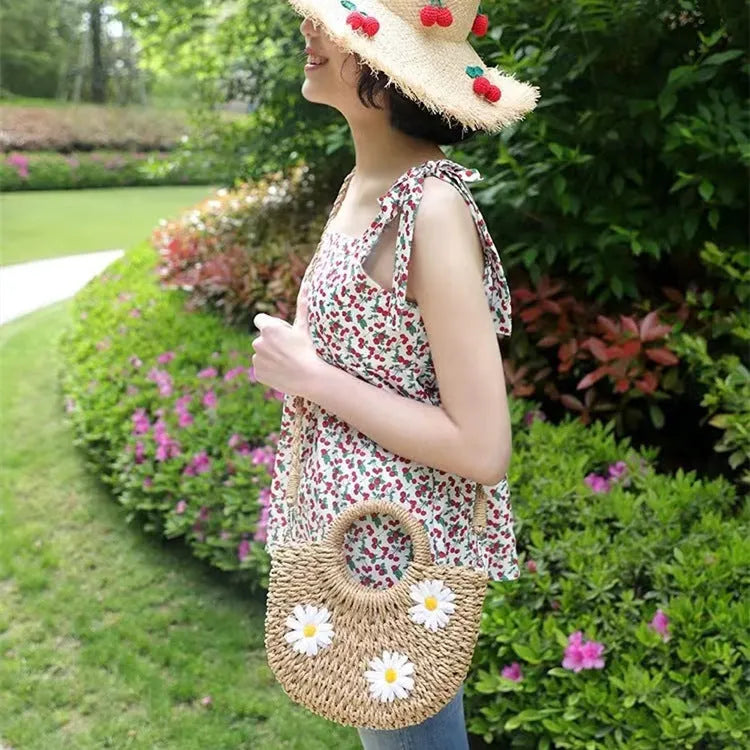 Women's light brown straw-weaved crossbody bag with daisy decoration showing woven texture