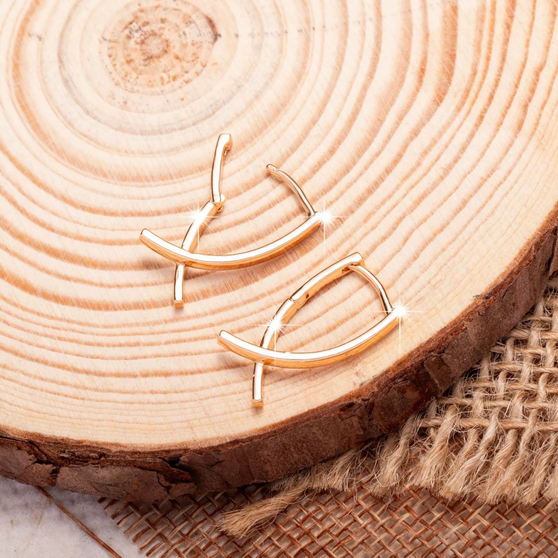 Rose gold tone cross-shaped copper earrings on a flat surface, showing polished finish and push-back clasp.
