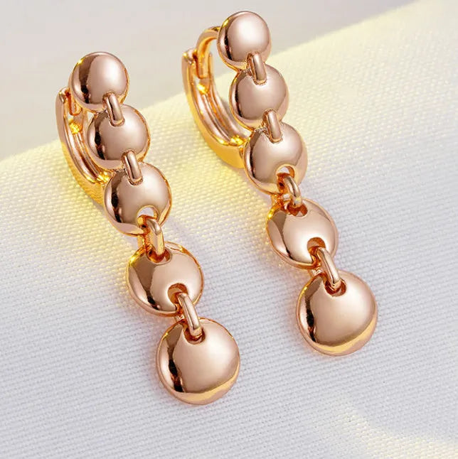 A pair of long, round circle-shaped retro earrings in a gold colour, made from woven copper