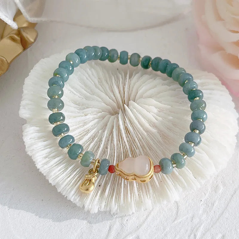 Women's simple jade bracelet with blue gourd charm and silver peace buckle on a beaded strand.