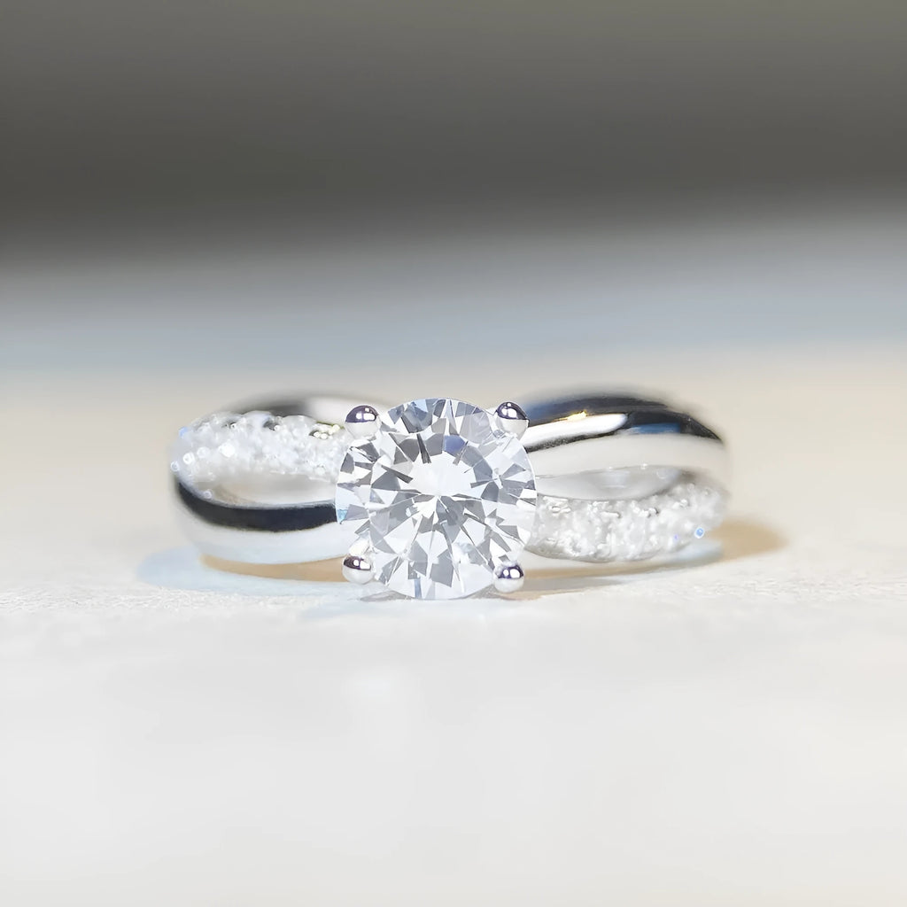 Silver ring with twisted geometric band and a 1 karat moissanite in a four-claw setting.