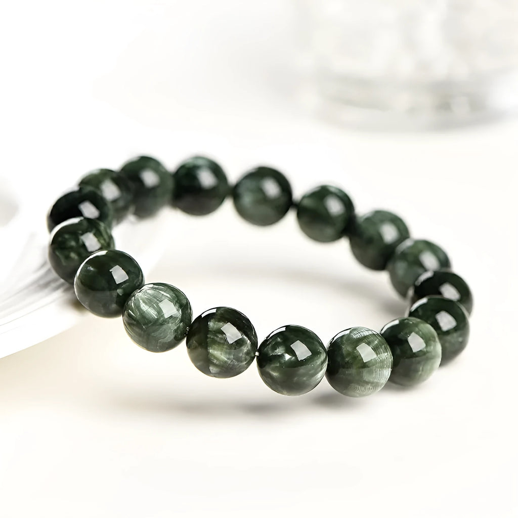 Close-up of a green dragon crystal bead bracelet with round geometry beads and a Ruyi charm.