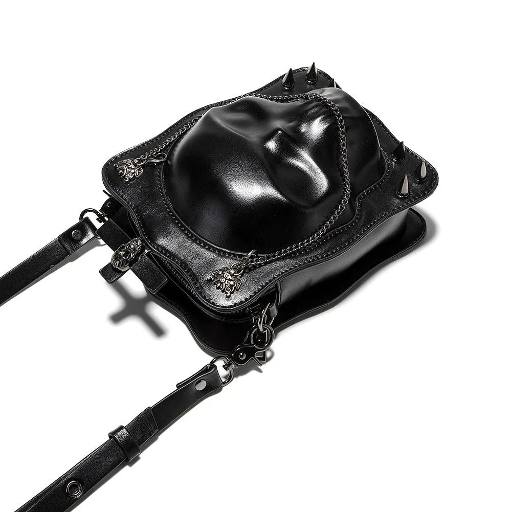 Black vertical square mini crossbody bag with embossed skull design, metal chain strap, and zipper closure