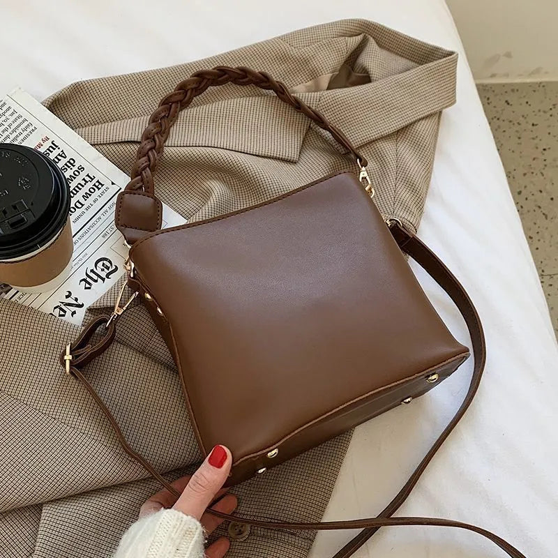 Retro khaki woven crossbody bucket bag with adjustable strap shown worn on shoulder