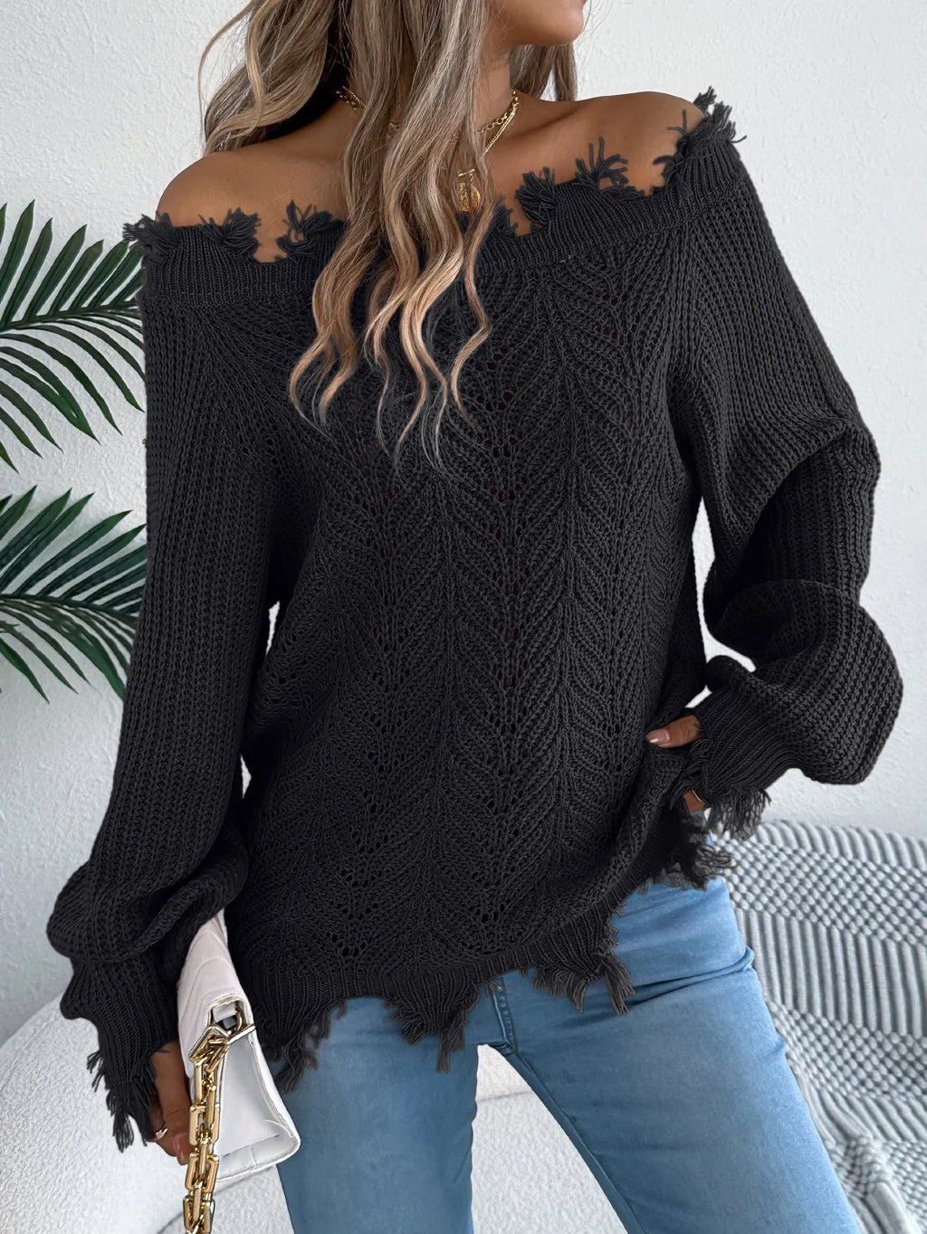 White hollow-out off-the-shoulder long sleeve pullover sweater laid flat.