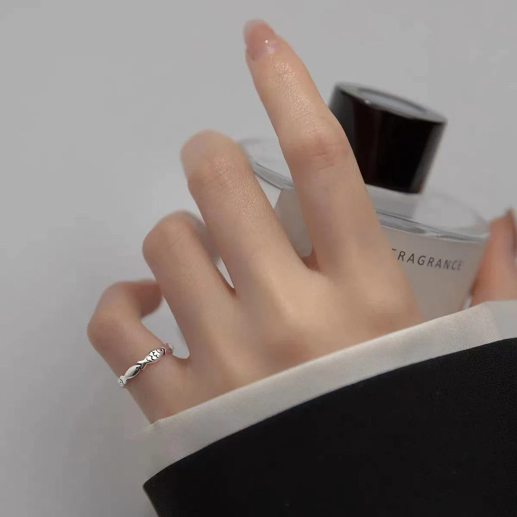 Close-up of a women's adjustable sterling silver ring with a vintage fish design on a finger.