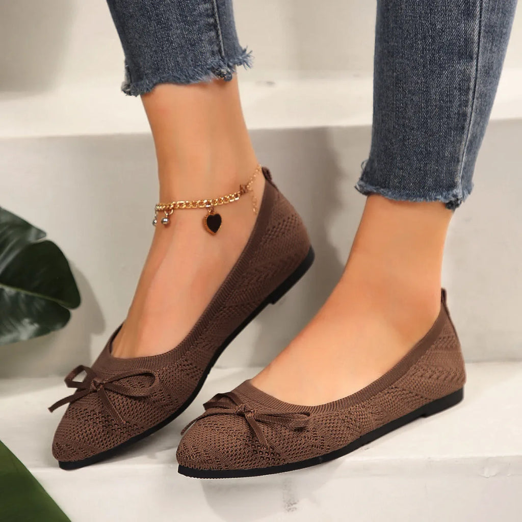 Women's blue knitted loafers with a bow detail and pointed toe on a flat rubber sole.