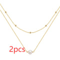 Close-up of a double-layer sterling silver necklace with twin pearl geometric pendants on a ball bead chain.