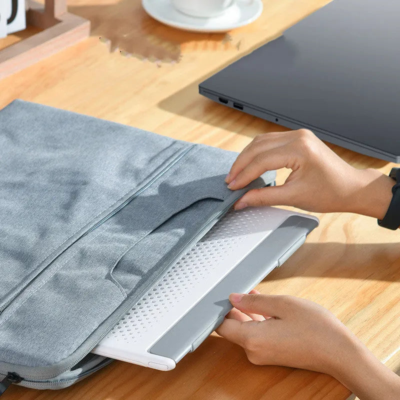 Portable black aluminium notebook stand folded flat next to a laptop