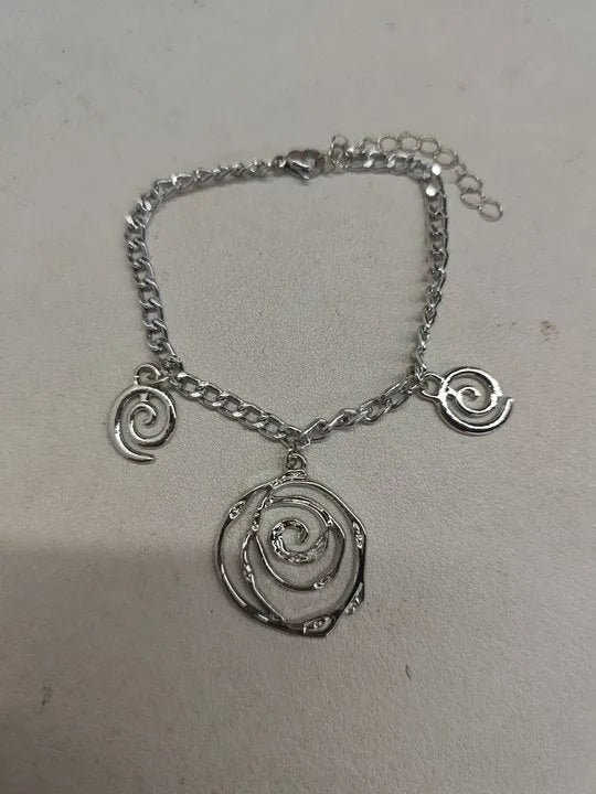 Gold spiral donut pendant necklace, matching bracelet and ear hooks set on a grey background.