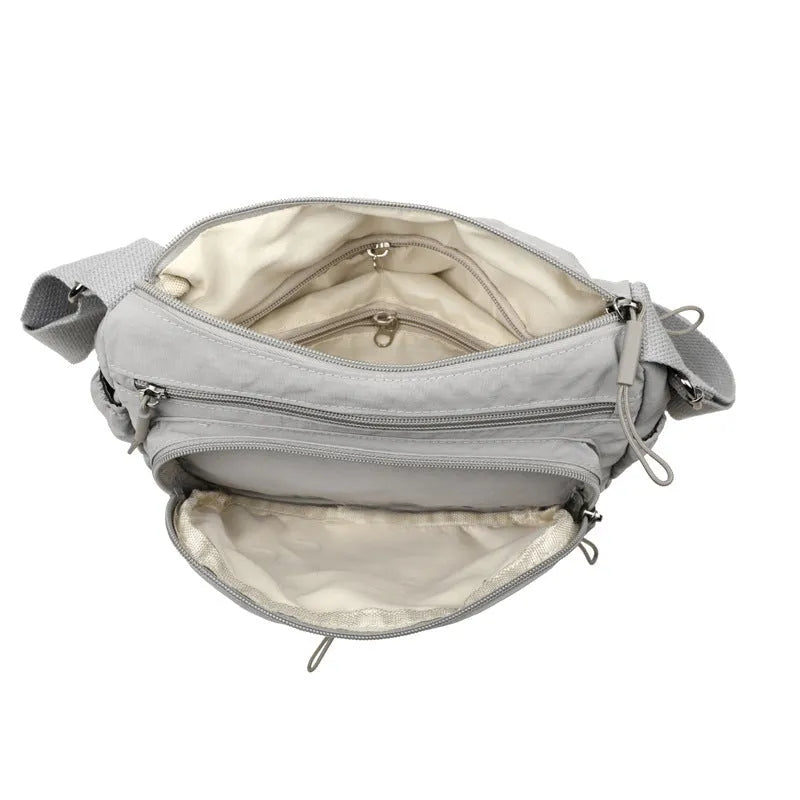 Soft water-repellent nylon crossbody bag in black with an outer pocket and zipped main compartment.