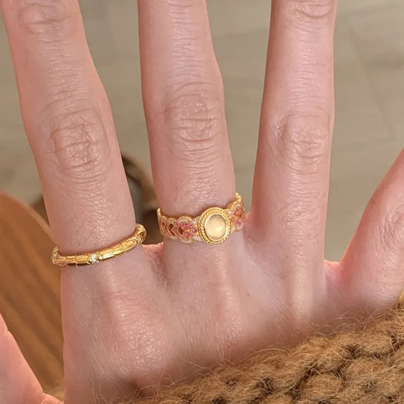 Close-up of a women's adjustable open ring with pink crystal enamel on a geometric gold-plated band.