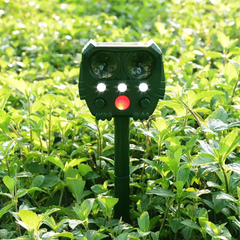 Green solar-powered ultrasonic animal repeller with LED strobe lights for outdoor pest control.