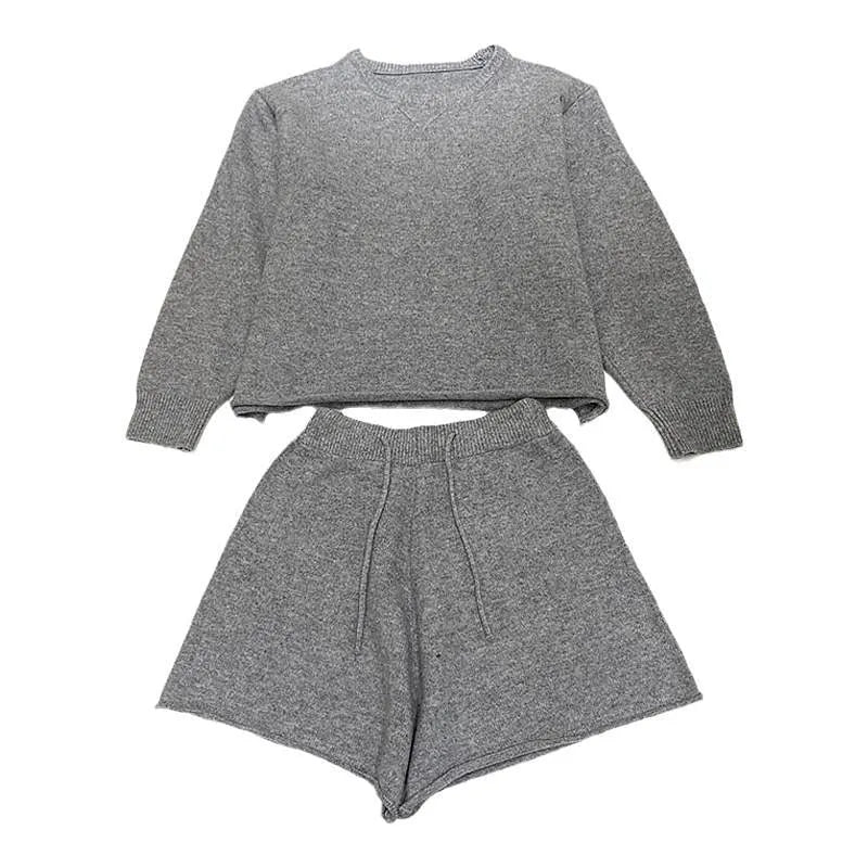 Woman wearing a loose grey knitted long-sleeve sweater and matching wide-leg shorts two-piece set.