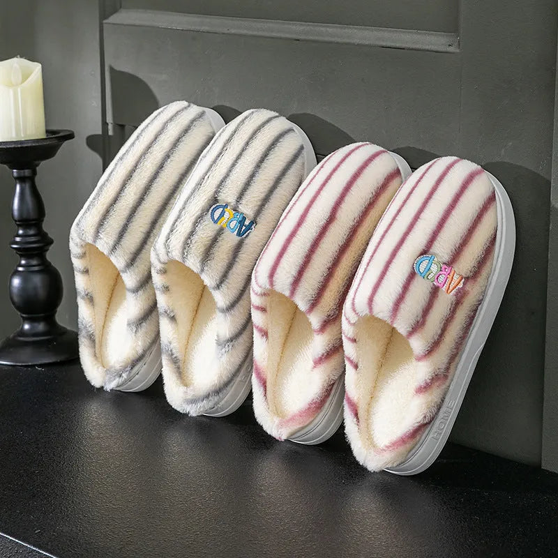 A pair of colourful vertically striped cotton flip flop slippers for adults on a plain background.