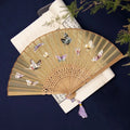 Folding hand fan with embroidered silk design on bamboo frame, shown in 7-inch size