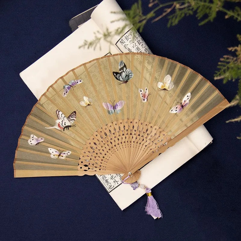 Folding hand fan with embroidered silk design on bamboo frame, shown in 7-inch size