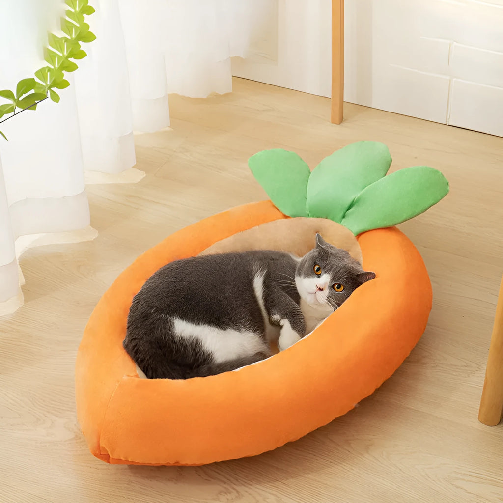 Orange carrot-shaped dog nesting bed with a raised bolster edge and a separate soft blanket, shown in two sizes.