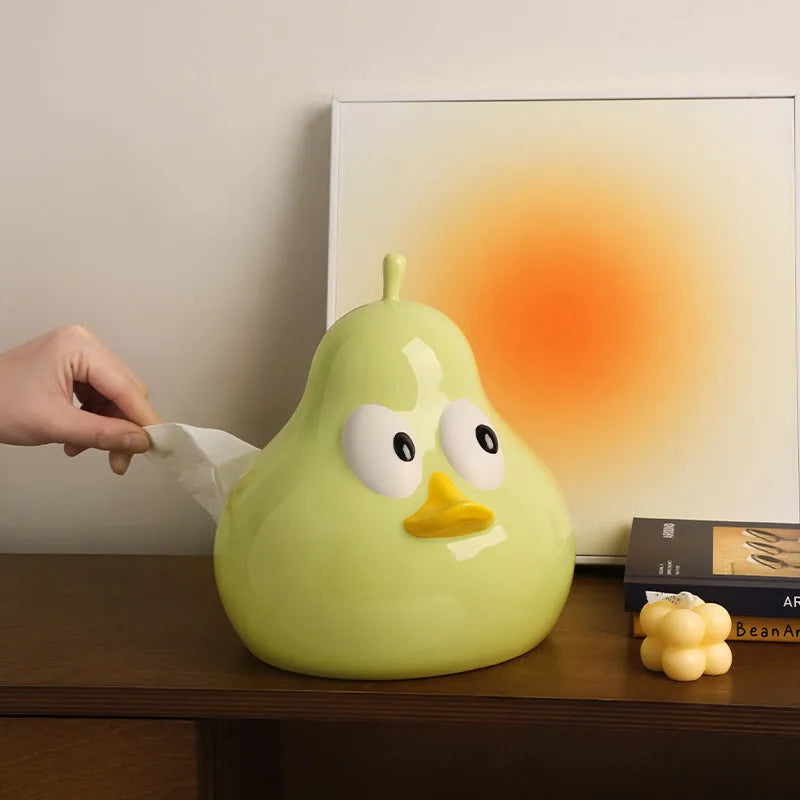 Green ceramic pear-shaped tissue box holder on wooden desk