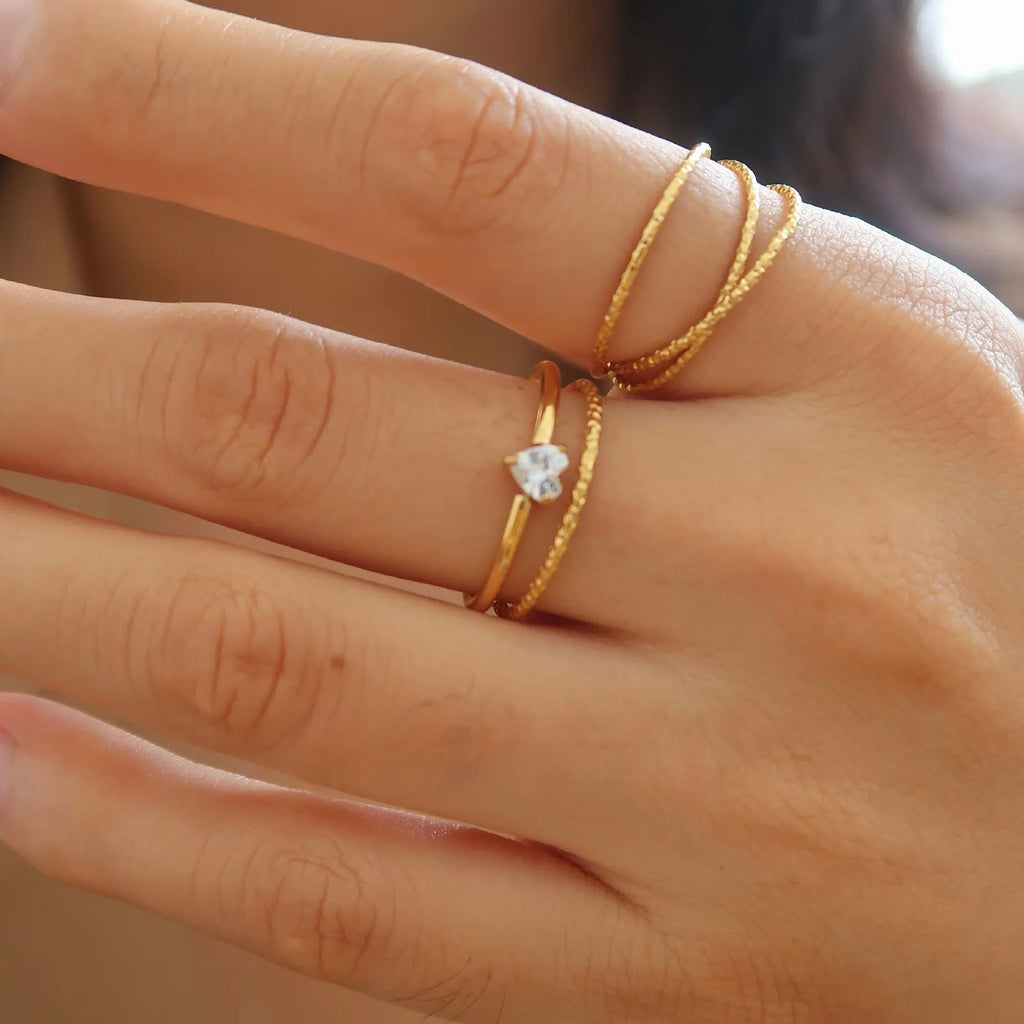 Gold heart-shaped ring and gold oval ring on display, both in stainless steel for women.